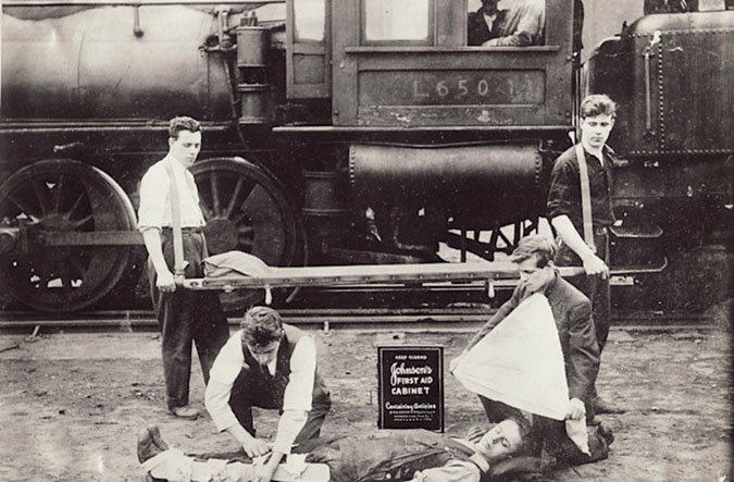 A rail crew in 1916 demonstrates the use of a first-aid kit on an uninjured volunteer. Operating rules have changed since 1916.